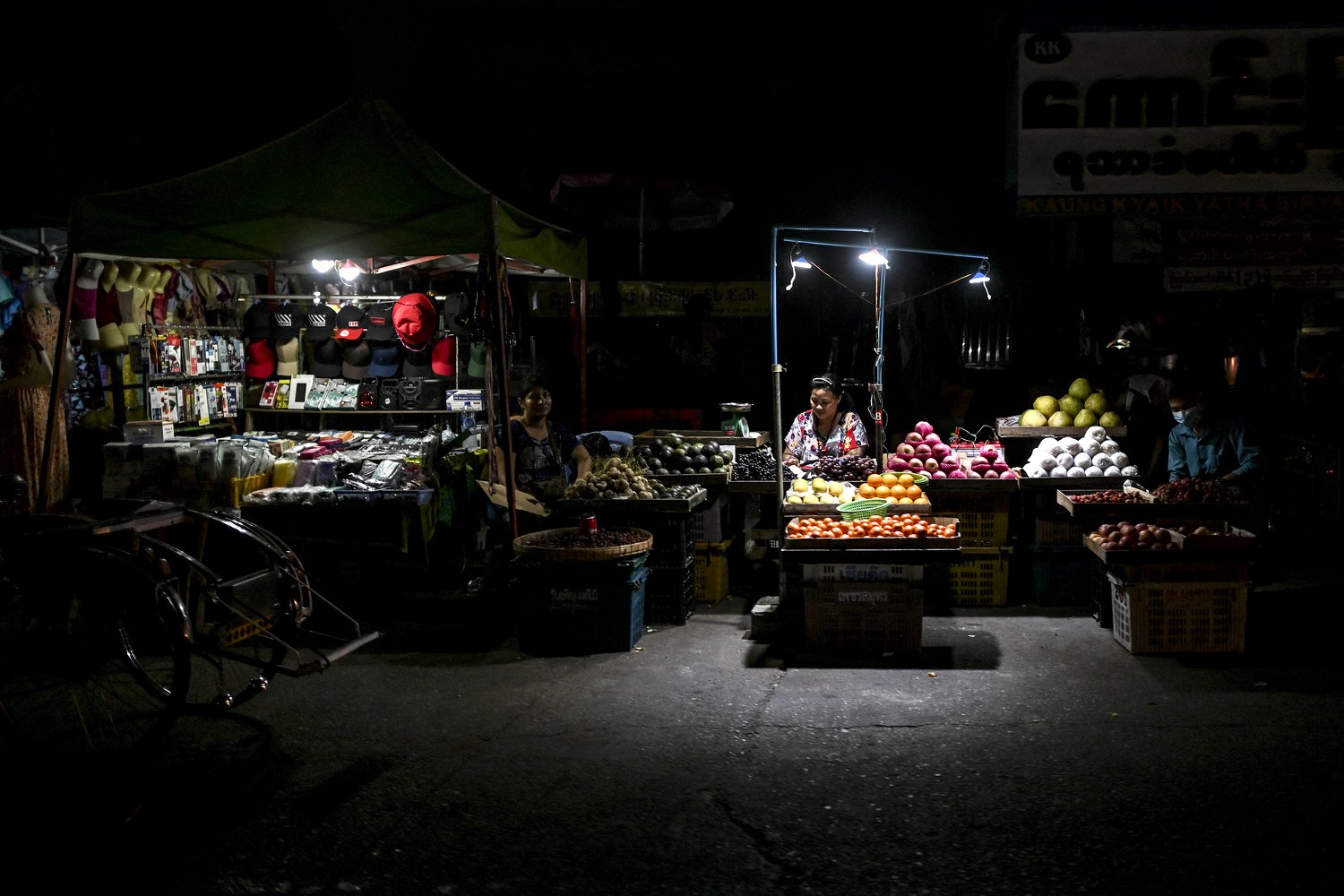 Street vendors wait for customers March 3, 2022, during one of the frequent power outages in Yangon, Myanmar. Economic mismanagement has hamstrung the military's budget. Credit: AFP